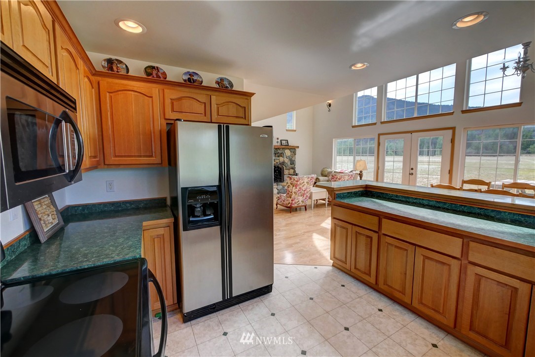 36 Beaver Pond Road Twisp, WA 98856 - Photo 21 of 40 a kitchen with stainless steel appliances granite countertop a refrigerator a stove and a sink with wooden cabinets