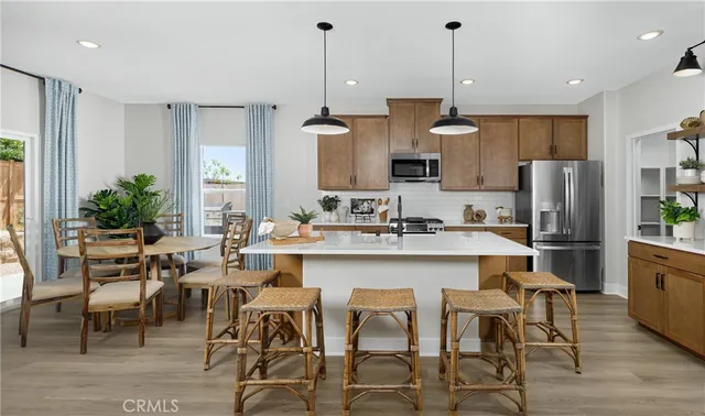 a kitchen with stainless steel appliances a dining table chairs refrigerator and sink