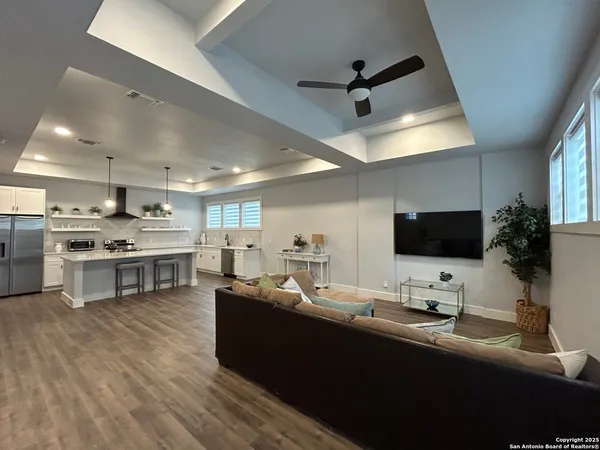 a living room with stainless steel appliances kitchen island furniture and a flat screen tv
