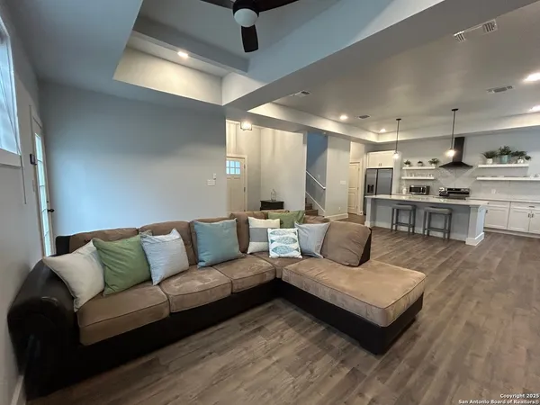 a living room with furniture kitchen view and a wooden floor