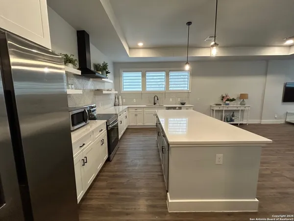 a kitchen with stainless steel appliances a refrigerator a sink a stove and white cabinets