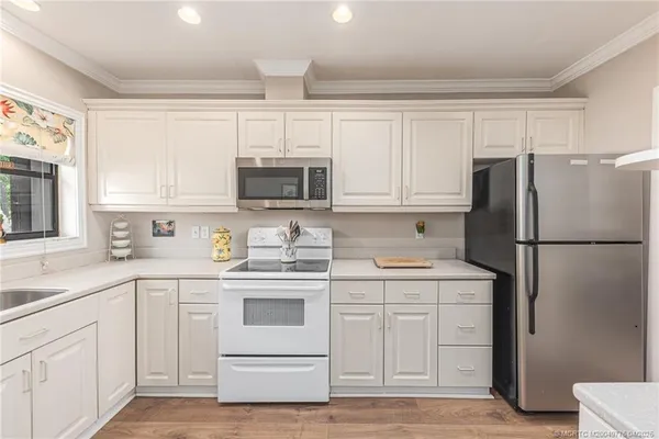 a kitchen with a sink dishwasher a stove and white cabinets with wooden floor