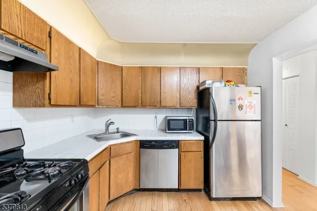 a kitchen with refrigerator a stove a sink and cabinets