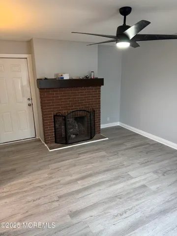 an empty room with wooden floor a fireplace a ceiling fan and wooden floor