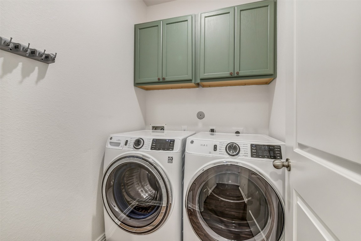 29519 Crimson Beech Drive Spring, TX 77386 - Photo 17 of 22 This laundry room features modern front-loading washer and dryer units (excluded), green overhead cabinets for storage, and a sleek, minimalist design.