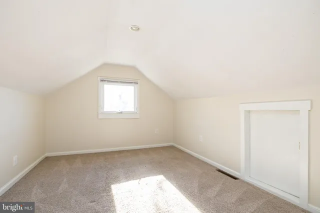 a view of an empty room with closet and a window