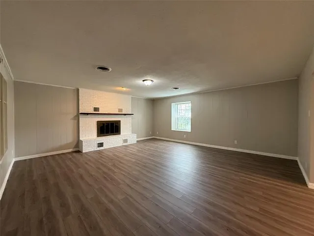 a view of empty room with wooden floor and fireplace