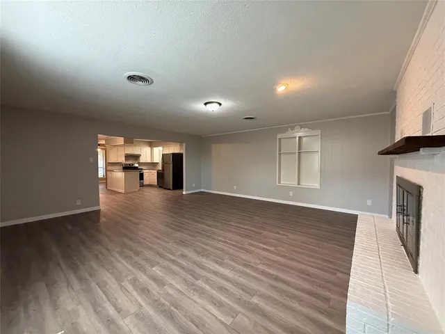 an empty room with wooden floor fireplace and windows
