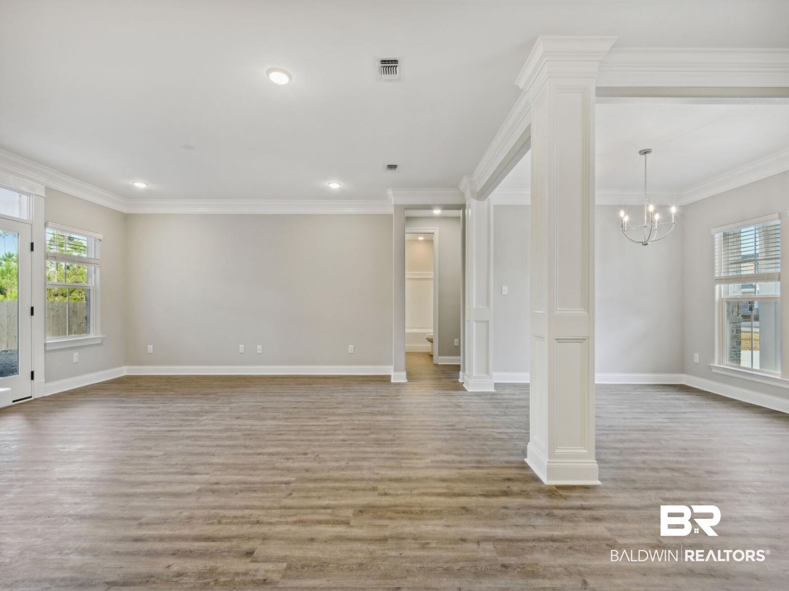 12943 Gondala Street Elberta, AL 36530 - Photo 7 of 23 Unfurnished living room featuring plenty of natural light, light wood-style flooring, a chandelier, ornamental molding, and recessed lighting