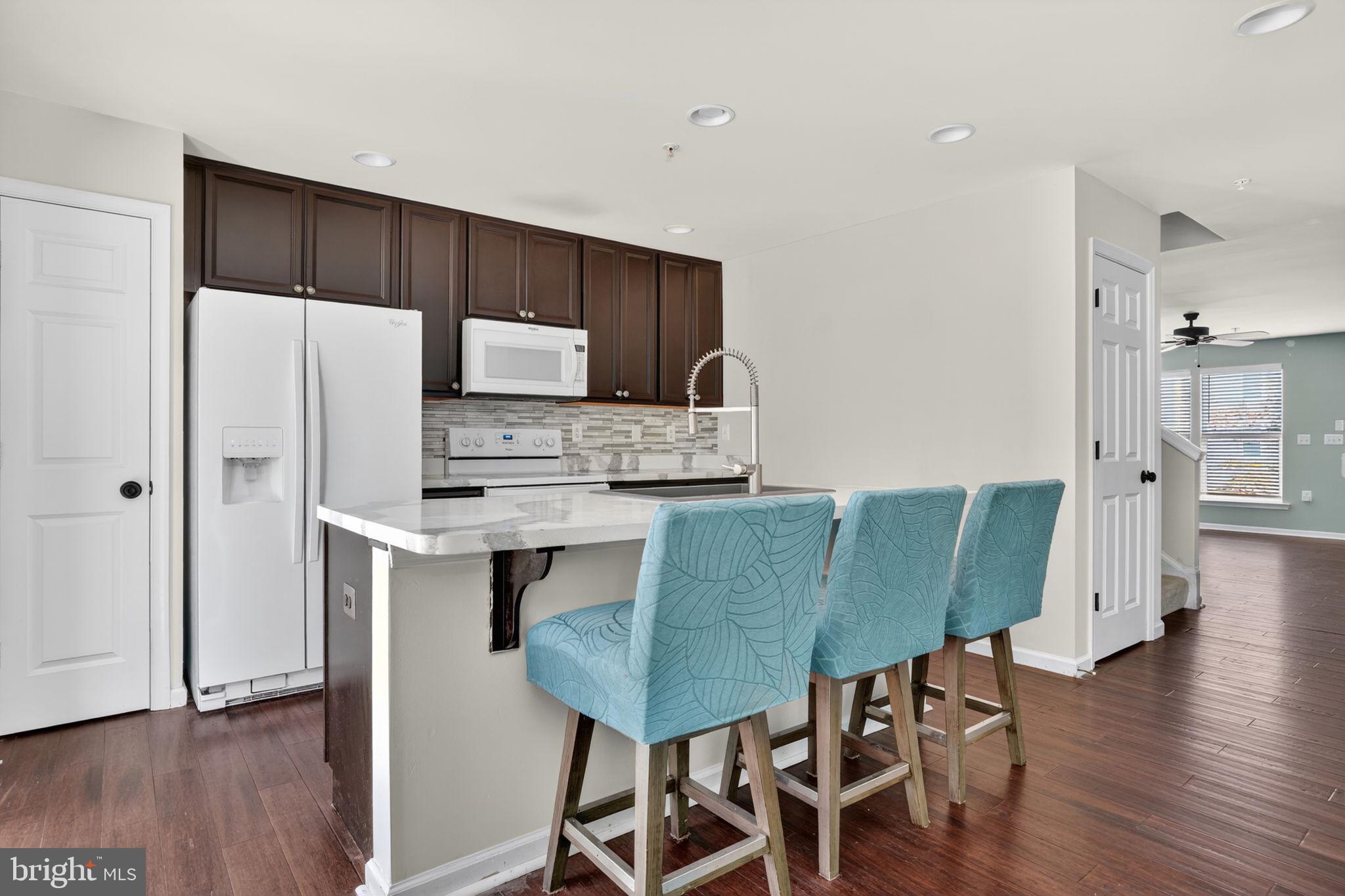 158 Intrepid Lane, Unit 92 Berlin, MD 21811 - Photo 11 of 37 a kitchen with stainless steel appliances a table chairs refrigerator and microwave