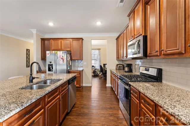 a kitchen with stainless steel appliances granite countertop a sink a stove and a wooden floors