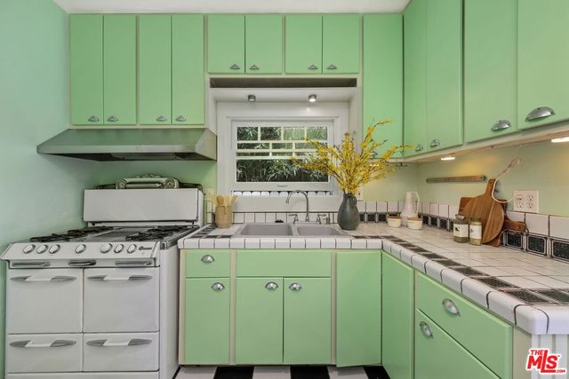 a kitchen with granite countertop a stove a sink and dishwasher wooden cabinets with wooden floor