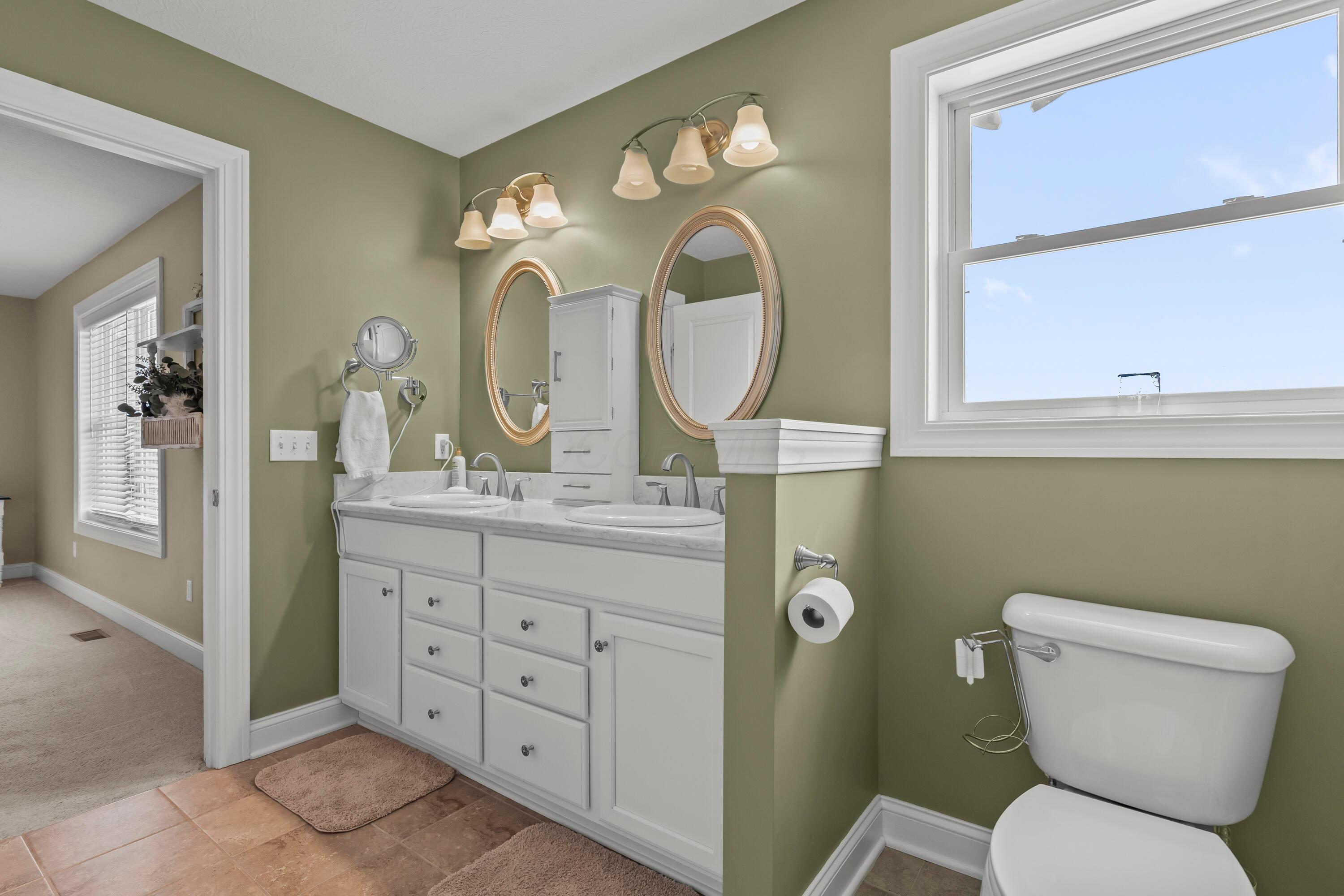 3582 Panhandle Road Delaware, OH 43015 - Photo 14 of 65 • Ceramic tile flooring • Sage painted walls • Enclosed vanity with double bowl, quartz countertop • (2) 3 bulb wall lights • Mirror remains • Cabinet does not remain • Ceiling exhaust • Shower stall with glass doors • Magnifying mirror does not remain