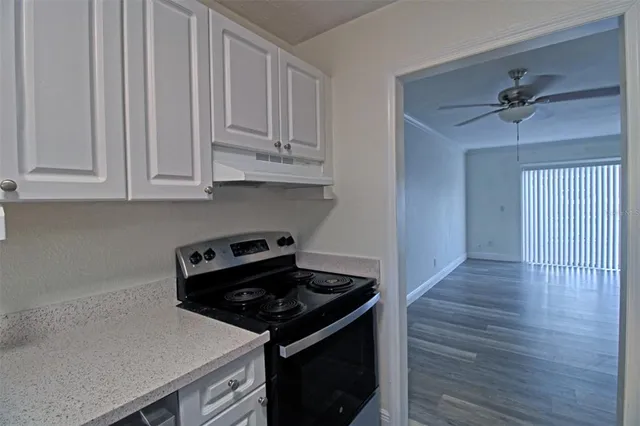 a kitchen with granite countertop a stove and a white cabinets