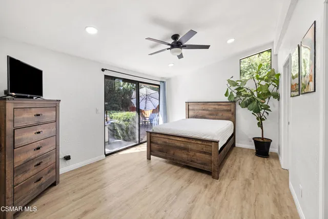 a spacious bedroom with a bed and a flat tv screen on dresser