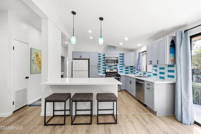 a kitchen with stainless steel appliances kitchen island a table chairs in it and wooden floors