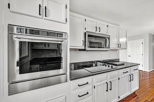 a kitchen with granite countertop stainless steel appliances and white cabinets