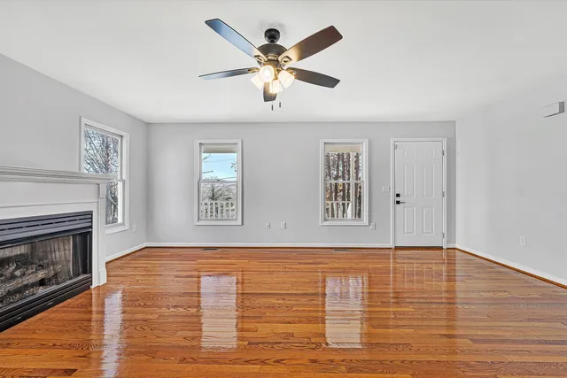 a view of an empty room with window and wooden floor