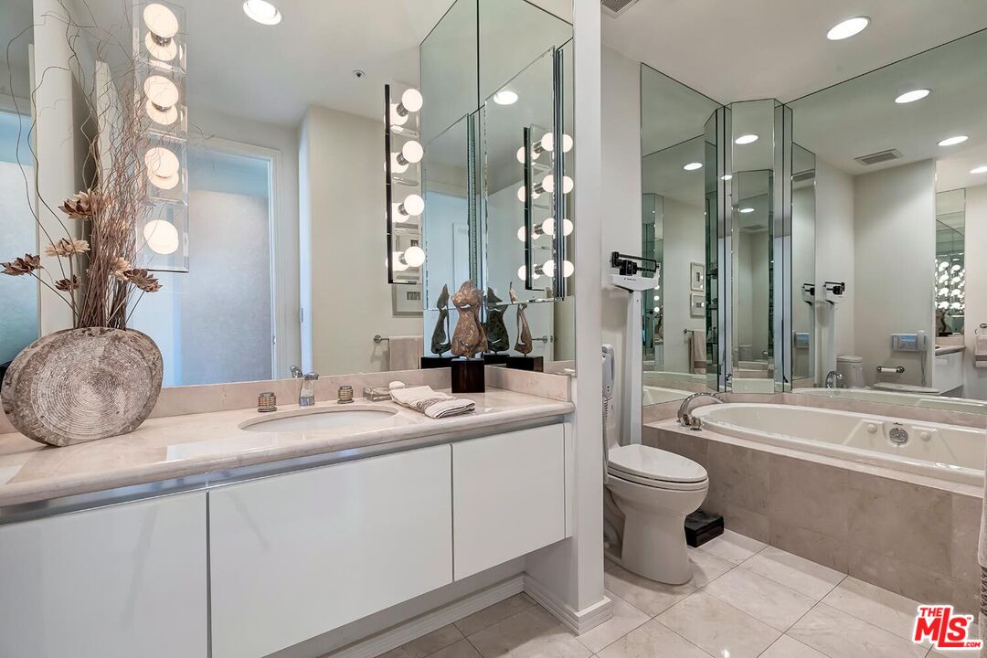 10380 Wilshire Boulevard, Unit 1703 Los Angeles, CA 90024 - Photo 29 of 34 a bathroom with a double vanity sink toilet mirror and bathtub