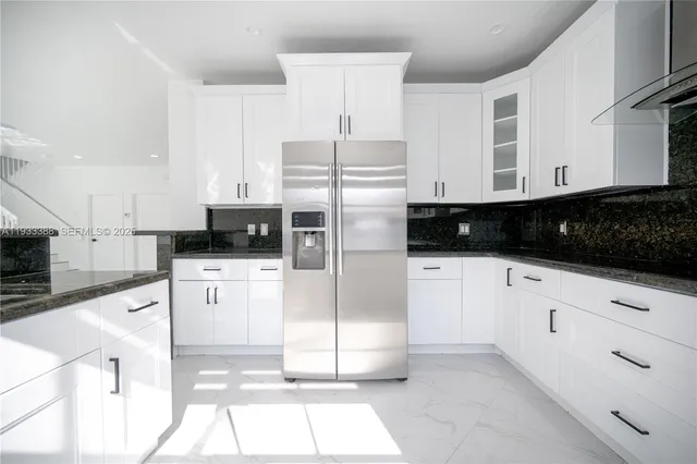 a kitchen with stainless steel appliances a refrigerator sink and white cabinets