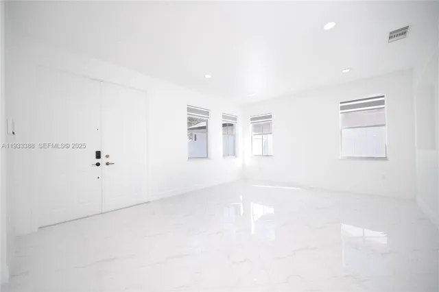 an empty room with white walls and windows