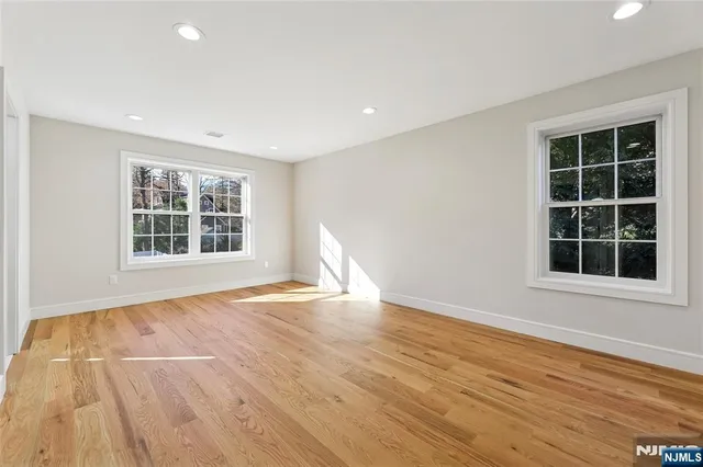 a view of an empty room with wooden floor and windows