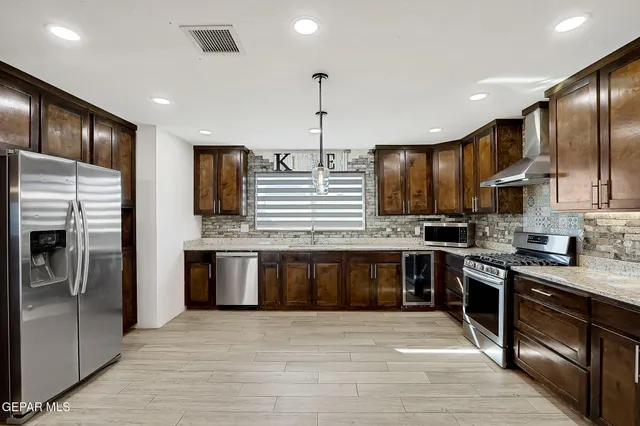 a large kitchen with stainless steel appliances kitchen island granite countertop a stove and a sink