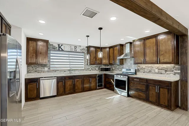 a kitchen with stainless steel appliances granite countertop a sink a stove and a wooden floors