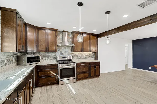 a kitchen with stainless steel appliances kitchen island a refrigerator and a wooden floor