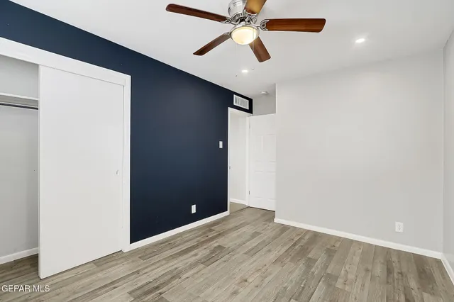 an empty room with wooden floor and fan