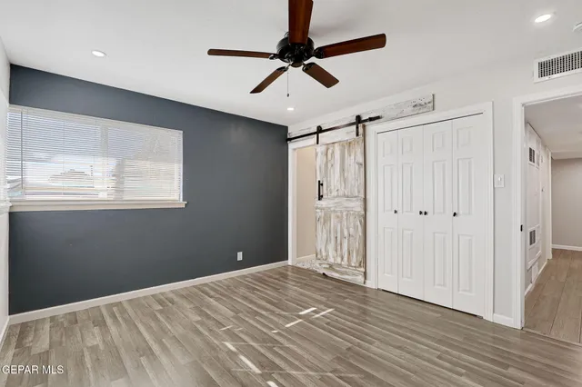 a view of empty room with wooden floor and fan