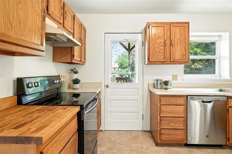 a kitchen with granite countertop a refrigerator and a stove top oven