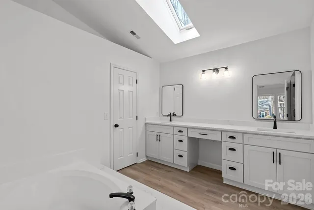 a spacious bathroom with a granite countertop sink a mirror and bathtub