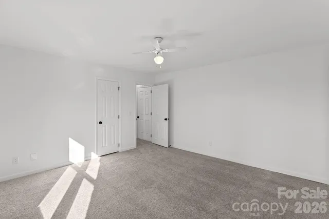 an empty room with windows and ceiling fan