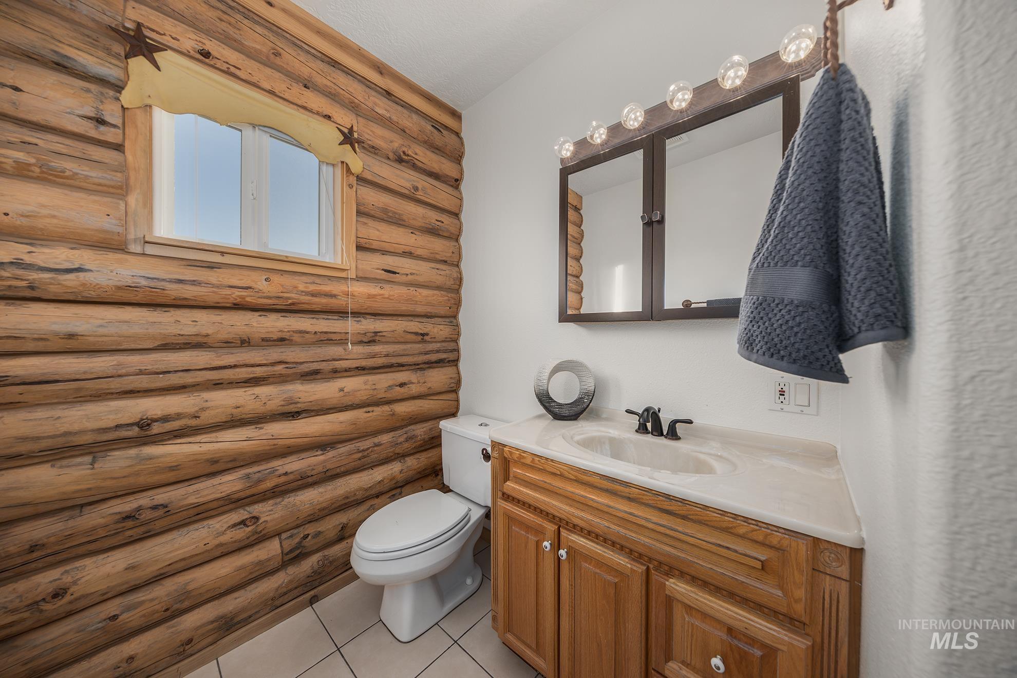 1855 Jones Road Weiser, ID 83672 - Photo 19 of 34 Half bathroom with vanity, rustic walls, and light tile patterned floors