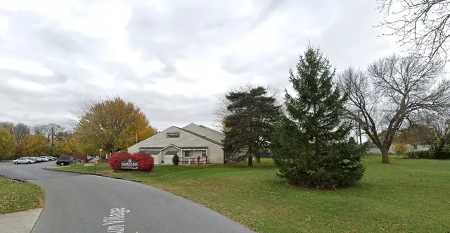 a front view of a house with a garden and trees