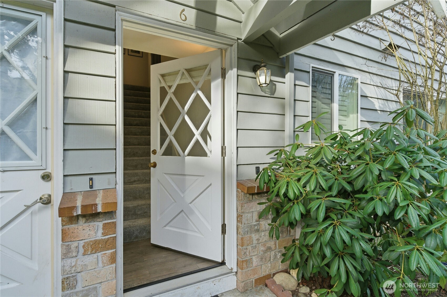 7909 218th Street Southwest, Unit 6 Edmonds, WA 98026 - Photo 24 of 27 a yellow house with a potted plant in front of door