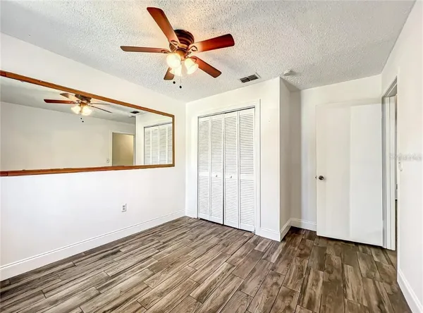 a view of empty room with wooden floor and fan