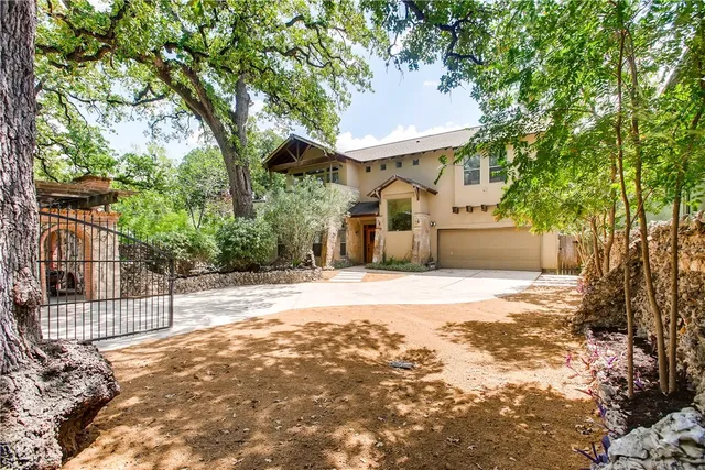 a view of a white house with a large tree and wooden fence