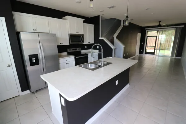 a kitchen with stainless steel appliances a sink dishwasher a refrigerator a stove top oven a counter space and cabinets
