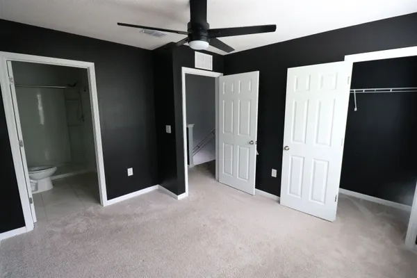 an empty room with closet and a chandelier fan
