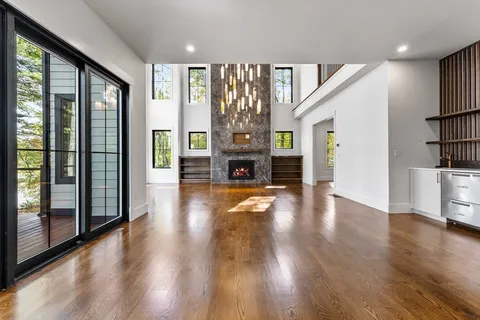 a view of a big room with wooden floor fireplace and windows
