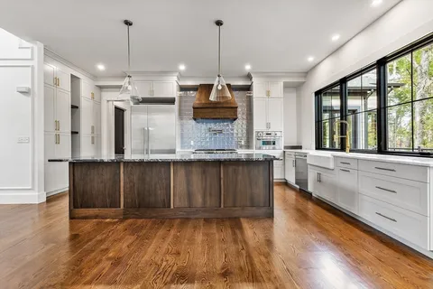 a large kitchen with kitchen island granite countertop wooden floors granite counter space a sink and a window