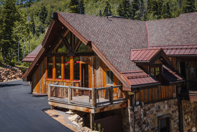 1667 West Tollgate Cyn Road Coalville, UT 84017 - Photo 53 of 61 Rustic exterior featuring wood siding, a stone foundation, a composition shingle roof, and a red metal roof accent