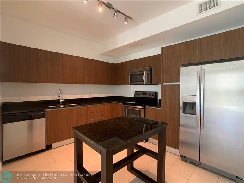 a kitchen with stainless steel appliances a refrigerator a stove a sink and a refrigerator