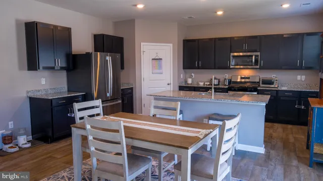 a kitchen with stainless steel appliances wooden cabinets granite counter tops a stove a sink and a refrigerator