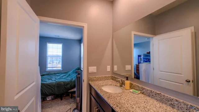 a en suite bathroom with a granite countertop sink and a mirror