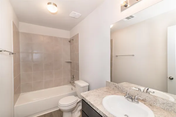 a bathroom with a bathtub shower sink vanity and toilet