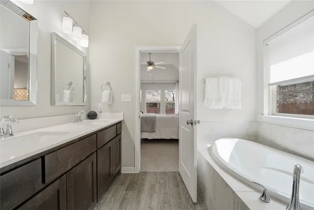 a en suite bathroom with a granite countertop tub sink a mirror a shower and vanity