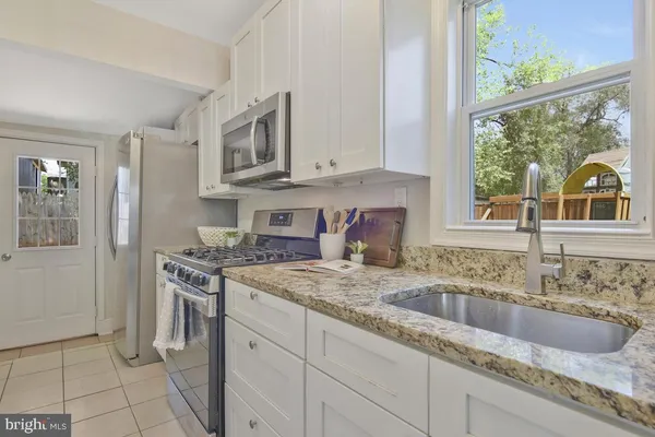 a kitchen with stainless steel appliances granite countertop a sink stove and a granite counter tops with white cabinets
